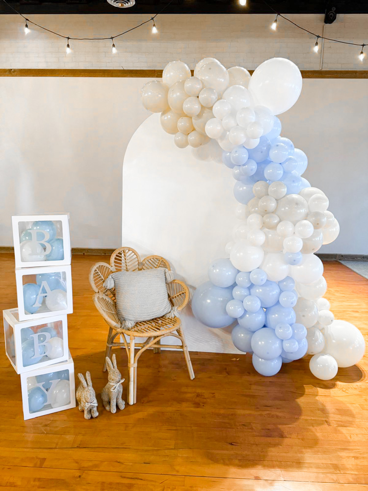 Wedding reception dessert table displaying a four-tier white cake and assorted pastries beneath a glowing Mr and Mrs neon sign